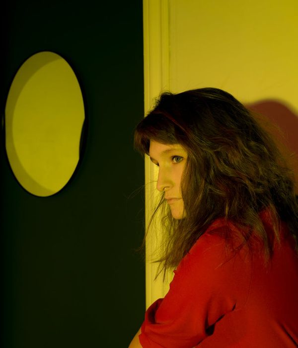Person in a calm yoga pose in a dark room with sunrise-colored light.